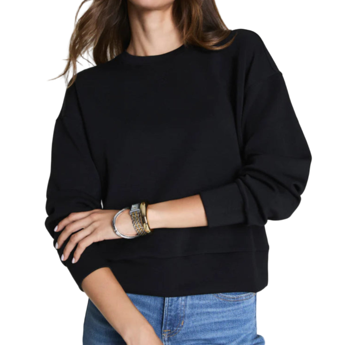 Woman wearing a black sweater and blue jeans against a plain background