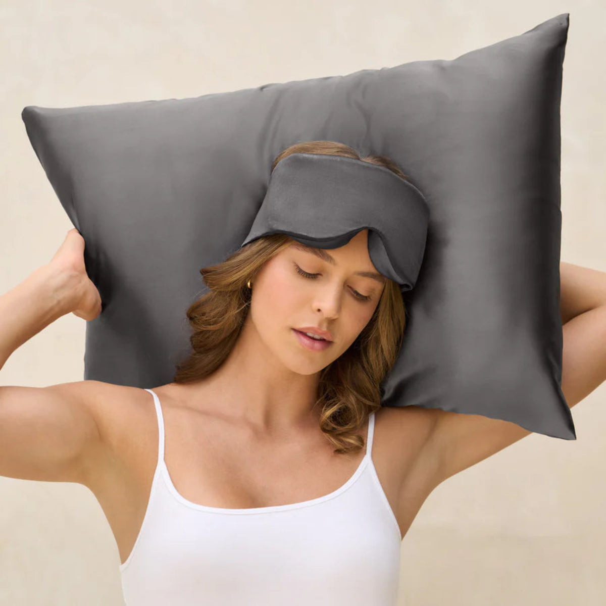 Woman wearing a gray sleep mask with a gray pillow behind her head Kitsch