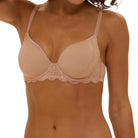 Woman wearing a beige bra and panties set against a beige background