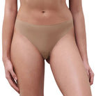 A model wearing a pair of high-waisted, low-rise briefs in a solid tan/beige color, shown from the waist down against a light gray background.
