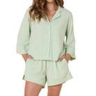 Woman wearing a light green pajama set against a white background
