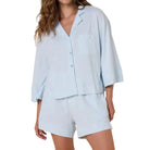 Woman wearing a light blue pajama set against a beige background