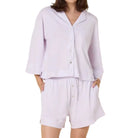 Woman wearing a lavender purple pajama set against a white background