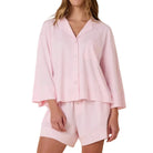 Woman wearing a pink pajama set on a white background