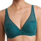 A close-up of a model wearing a teal lace bra with sheer mesh cups against a plain white background.