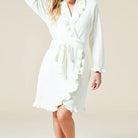 Woman wearing a white robe against a beige background