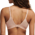 Woman wearing a beige bralette on a plain background