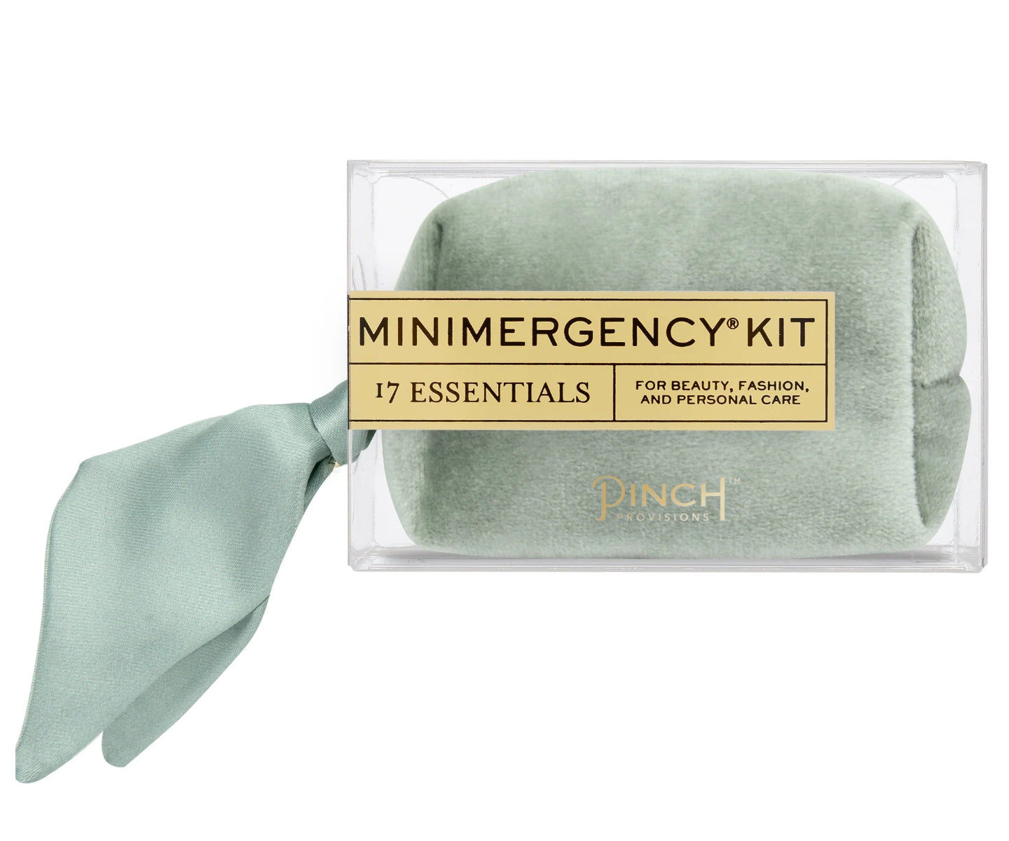 A packaged beauty and personal care kit labeled 'MINIMERGENCY KIT 17 ESSENTIALS' in a clear rectangular box, with a rolled pale sage green cloth inside and a matching satin ribbon tied to the front. The brand name 'PINCH' is visible near the bottom of the package.