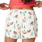 Person wearing a red top and patterned shorts with Christmas-themed designs on a plain background